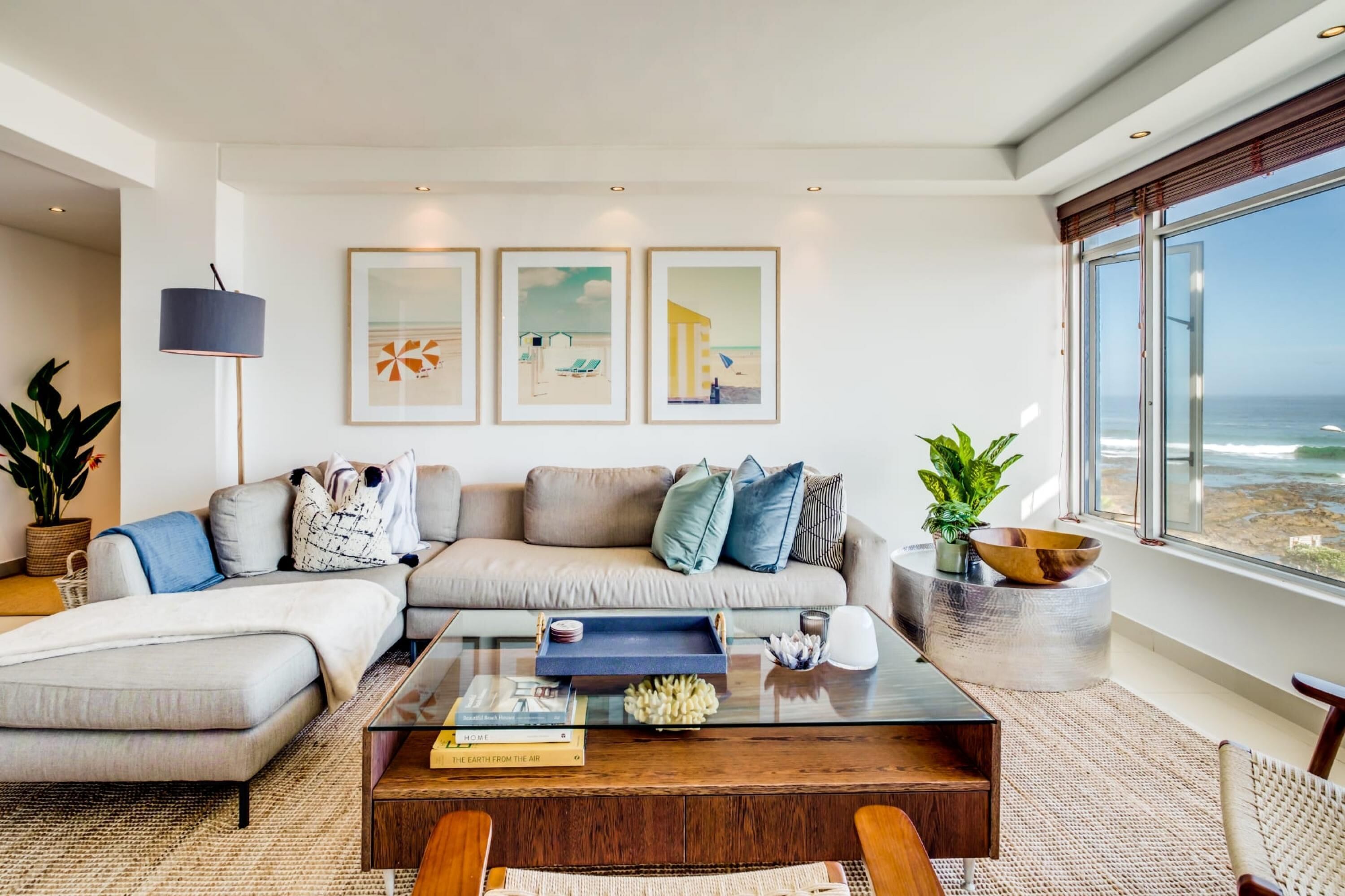 Una sala moderna con un sofá modular, una mesa de centro de vidrio y cuadros en la pared.