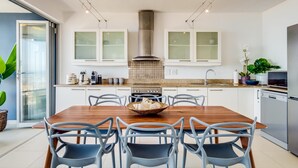 A modern kitchen with white cabinets, a central island with seating, and a stainless steel range hood. - Uninterrupted Ocean Views in Mouille Point Atlantic Vistas (Cape Town)