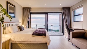 A modern bedroom with a large bed, a desk, and a view of the city. - Perfect Family Holiday Villa in Camps Bay Spindrift (Cape Town)