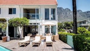 A modern house with a swimming pool, outdoor seating, and a view of mountains. - Magical Holiday Home Walking Distance to the Beach Sedgemoor Villa (Cape Town)