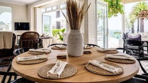 A round wooden dining table set with woven placemats and folded napkins, surrounded by chairs. - Magical Holiday Home Walking Distance to the Beach Sedgemoor Villa (Cape Town)