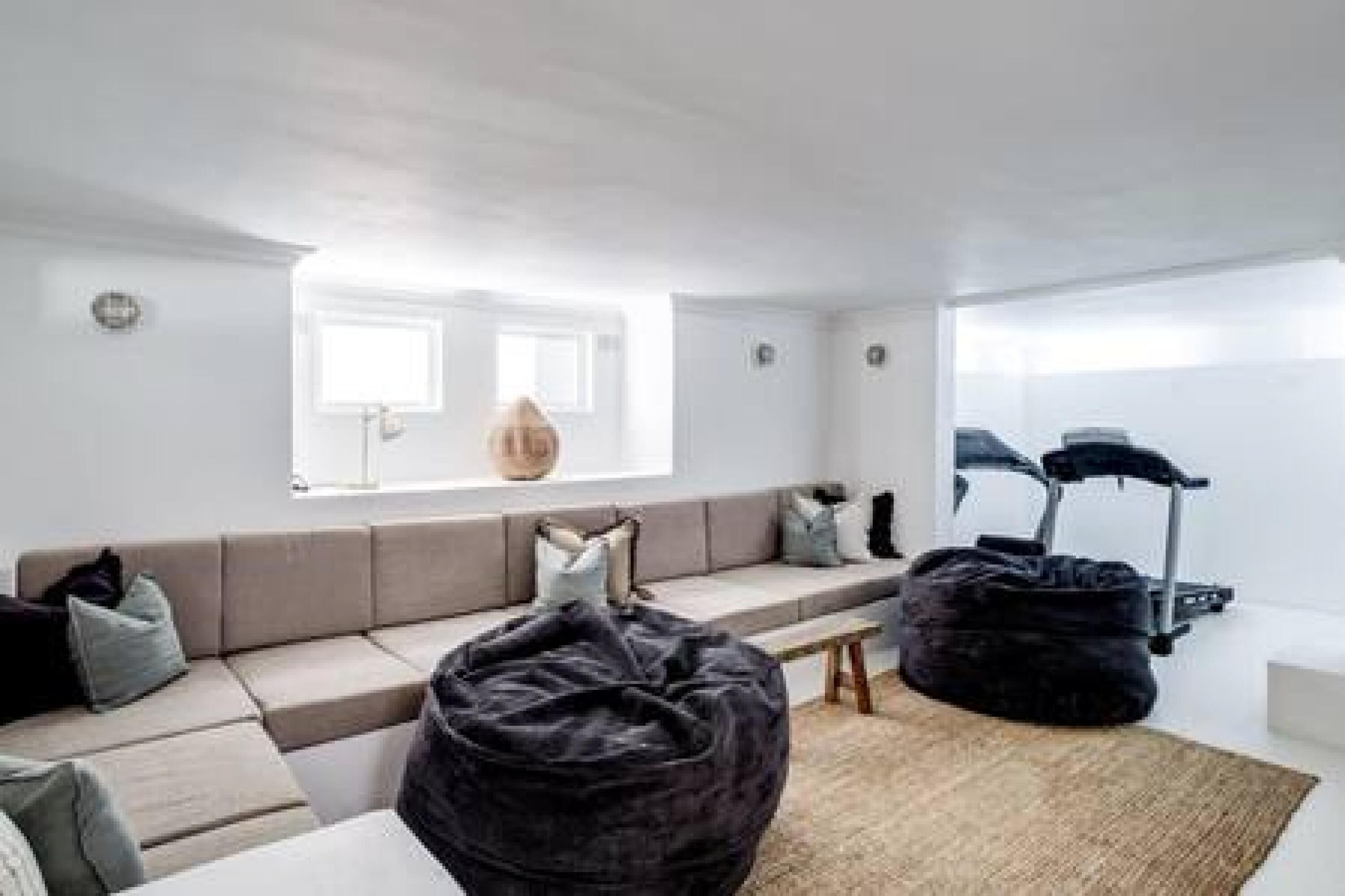 A modern living room with a sofa, bean bag, and a treadmill.