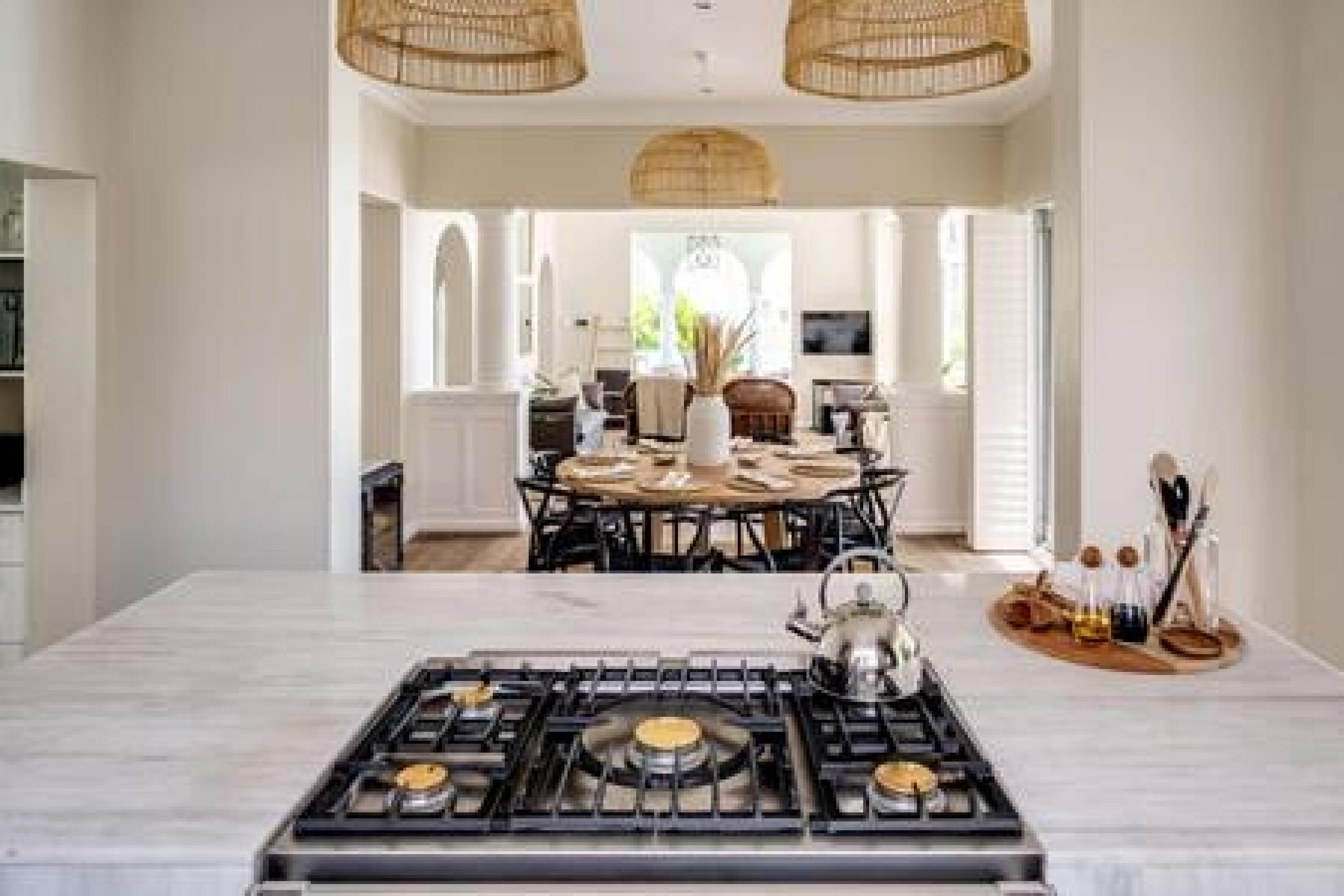 Une cuisine moderne dotée d’un îlot central, d’un coin repas avec une table ronde et d’une vue sur le salon.