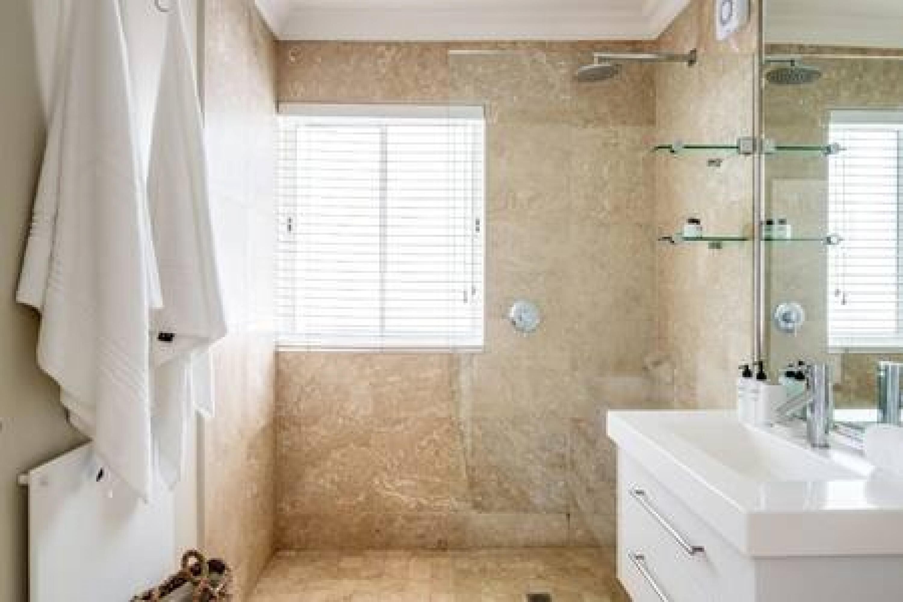 A bathroom with a shower, a glass-enclosed vanity, and a window.