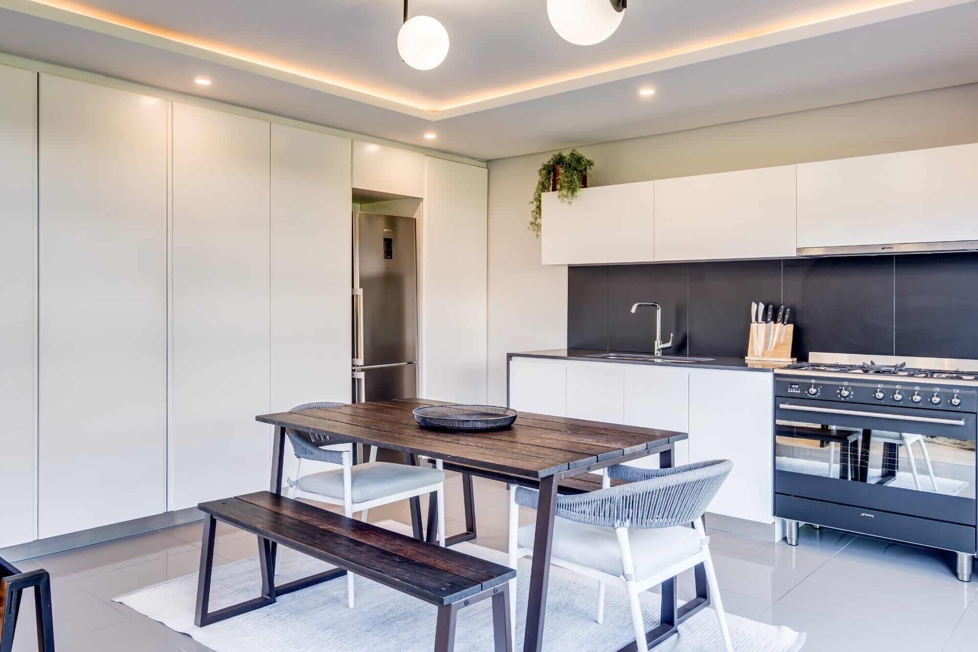 A modern kitchen with white cabinetry, a built-in oven, and a stainless steel refrigerator.