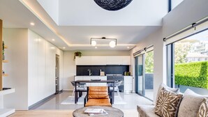 Une cuisine moderne avec un coin repas, une table basse ronde et un canapé agrémenté de coussins à motifs.
