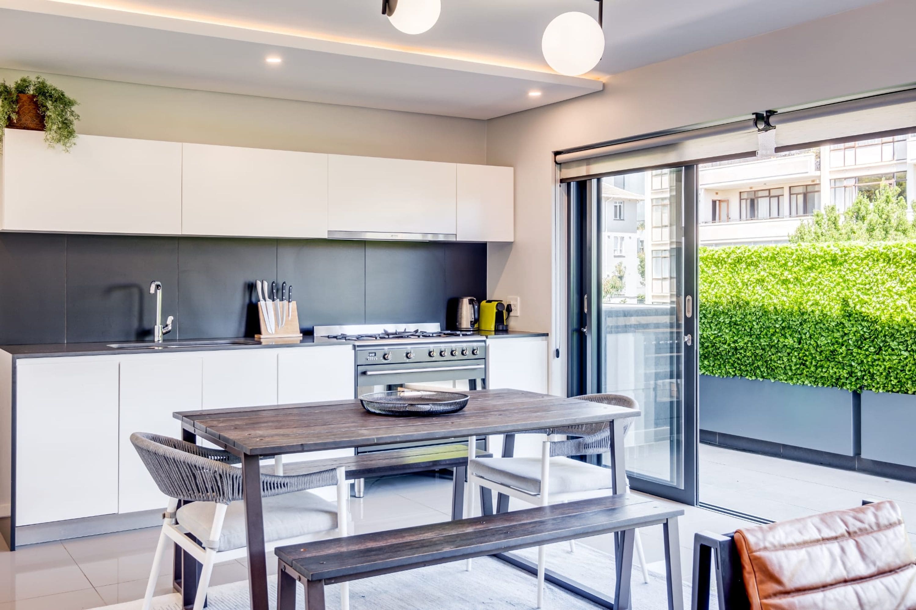 A modern kitchen with white cabinets, a gas stove, and a dining area with a wooden table and chairs.