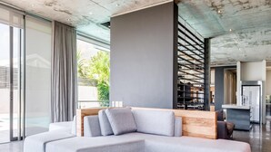 Ein modernes Wohnzimmer mit einem grauen Ecksofa, einem Holztisch und einem runden Hocker.