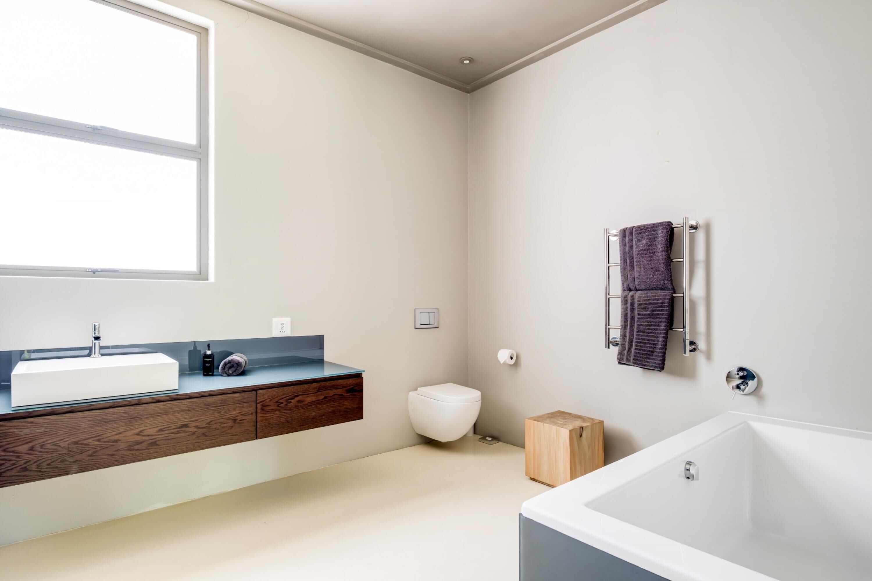 A modern bathroom with a white sink, wooden vanity, a white toilet, and a white bathtub.