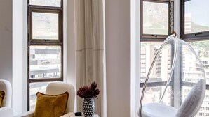 A modern living room with a hanging chair, a white sofa, and a small table with a vase. - Art Deco Loft in the Heart of Cape Town Splendid Loft (Cape Town)