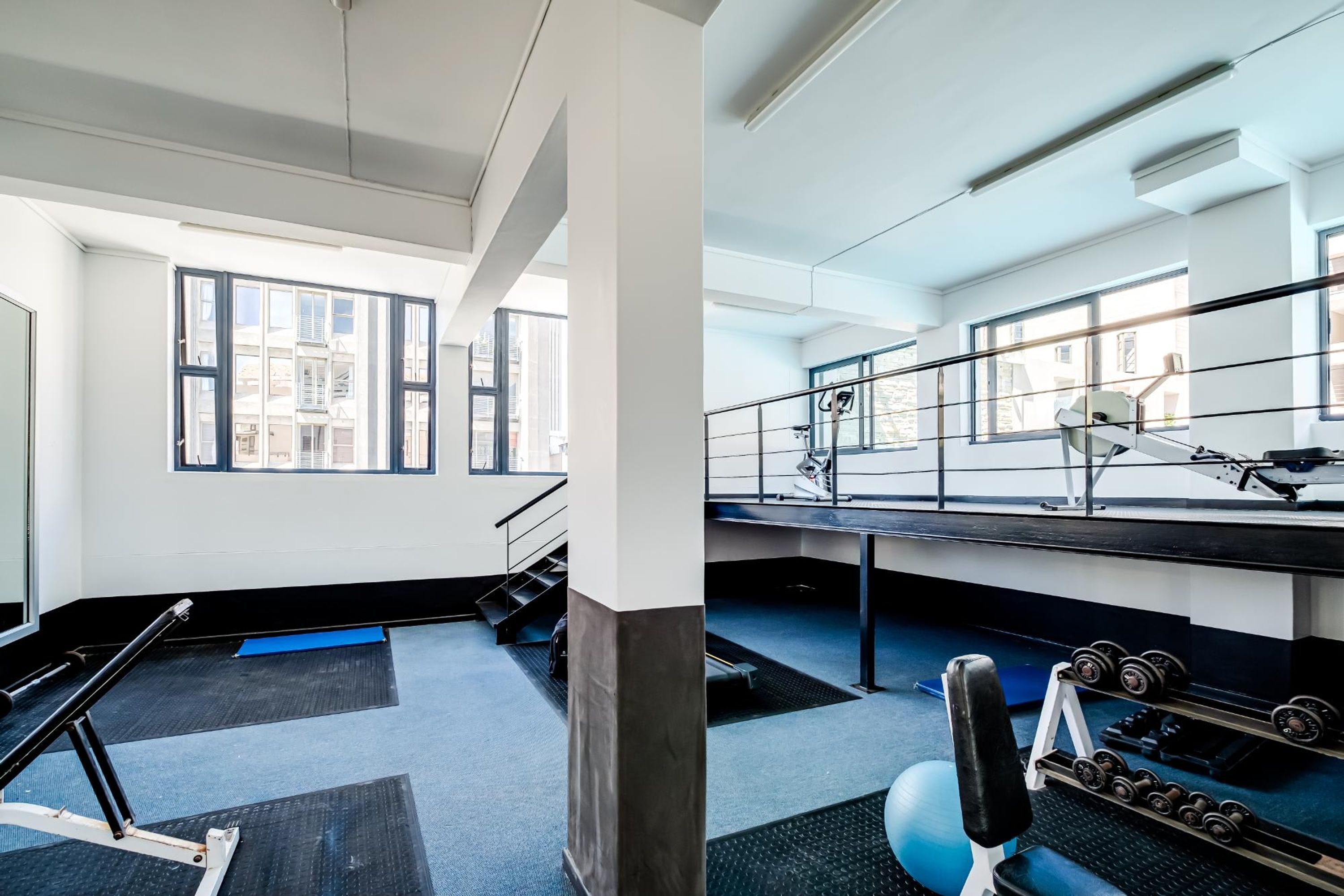 A gym with exercise equipment, large windows, and a view of buildings outside.