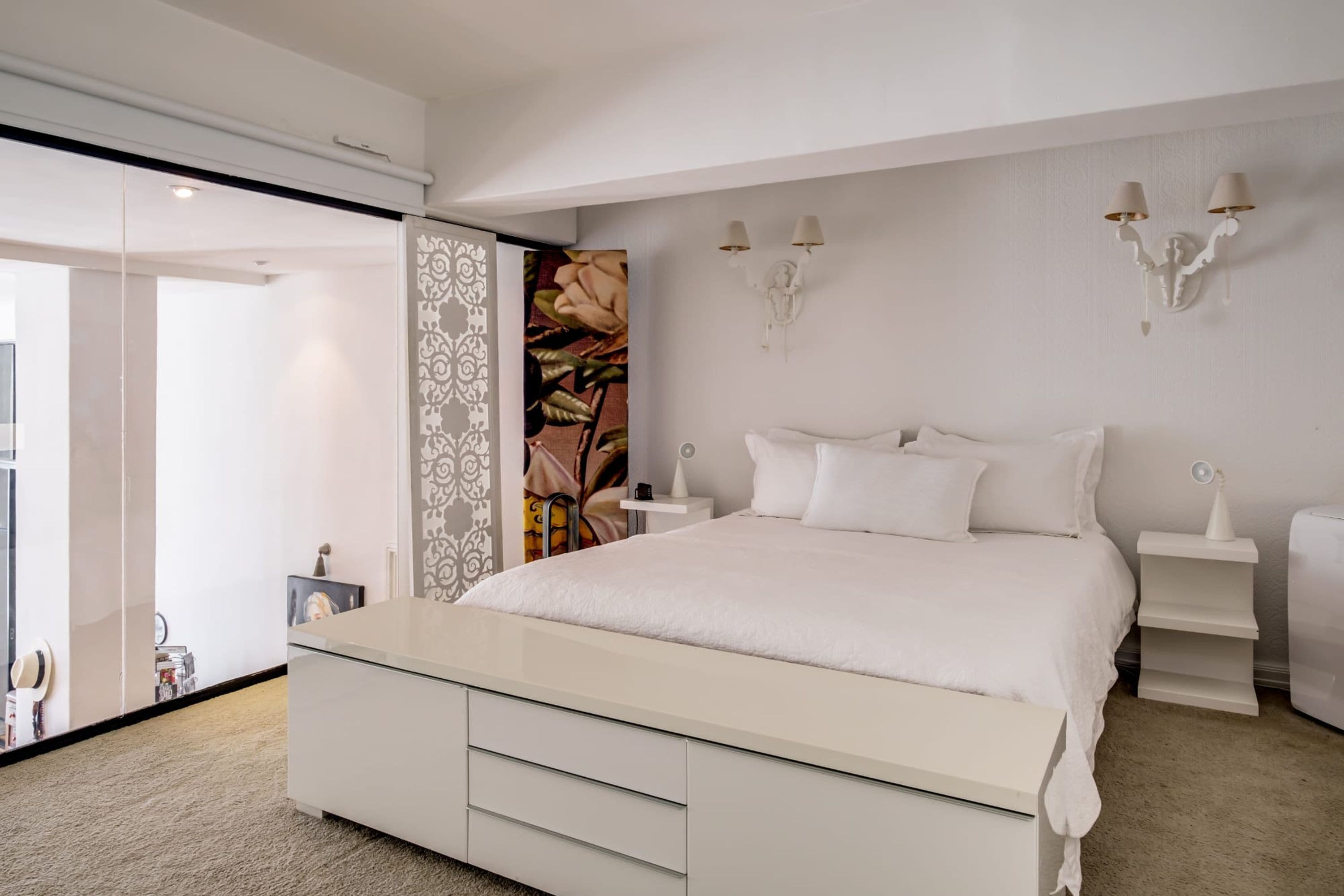 Un dormitorio moderno con una cama grande, mesitas de noche y un panel decorativo en la pared.