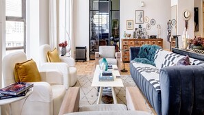 A spacious living room with a large window, a ceiling fan, a sofa, a coffee table, and a bookshelf. - Art Deco Loft in the Heart of Cape Town Splendid Loft (Cape Town)