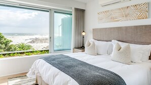 Ein Hotelzimmer mit großem Bett, Blick auf den Strand und modernem Design.