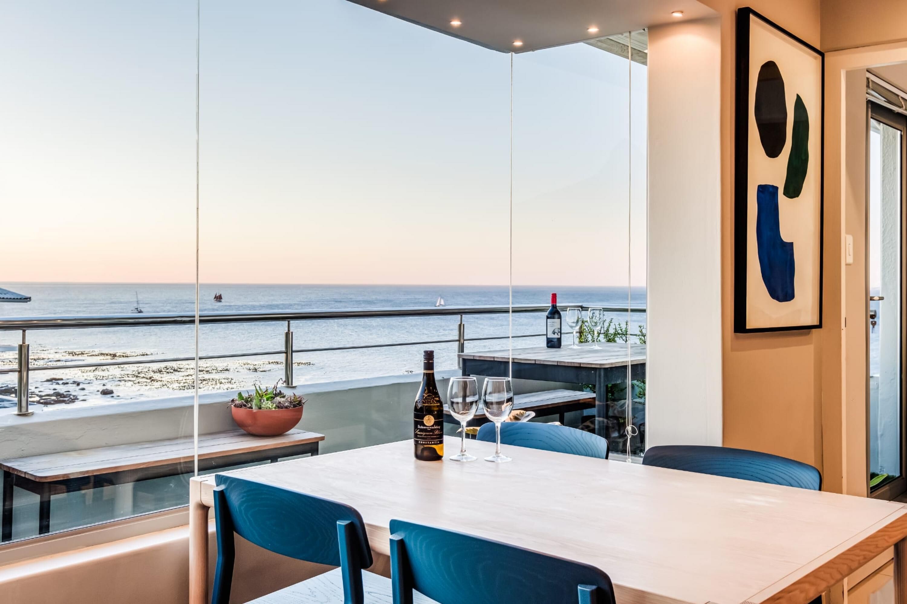 Een eetgedeelte met een tafel gedekt voor twee personen, met uitzicht op een strand.