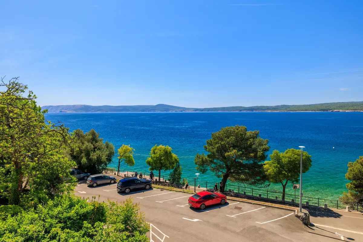 Un espace de stationnement avec des voitures, une vue dégagée sur la mer et un paysage côtier.