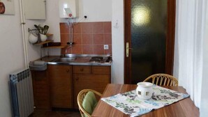 A compact kitchen with a dining table, chairs, a radiator, and a water heater. - Holiday apartment with air conditioning (Crikvenica)