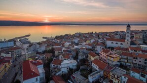 A coastal town with a prominent church tower, a calm sea, and a bridge in the distance. - Holiday apartment with air conditioning (Crikvenica)