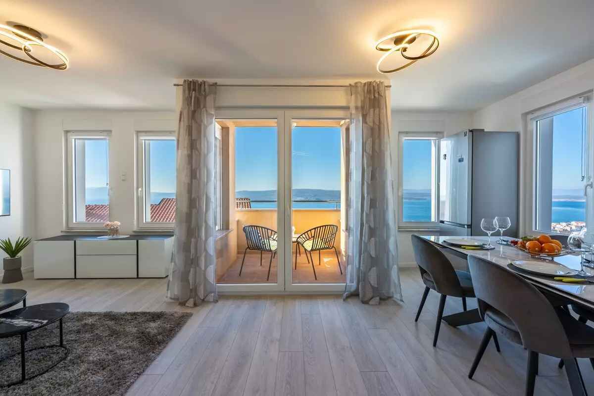 Een moderne keuken met een eetgedeelte, grote ramen en uitzicht op zee.