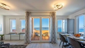 A modern kitchen with a dining area, large windows, and a view of the sea.