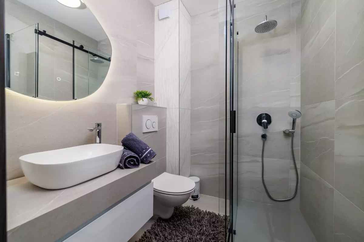 Ein modernes Badezimmer mit einer einteiligen Duschkabine, einem weißen Waschbecken und einer Toilette.