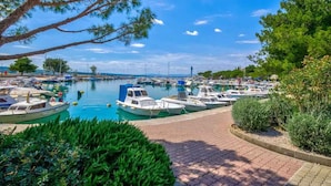 A marina with boats docked, a clear sky, and greenery around.