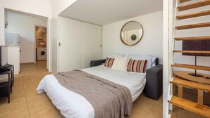 A bedroom with a bed, a bedside table, a mirror, and a staircase. - Studio with terrace and air conditioning (Crikvenica)