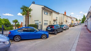 A street with parked cars, a palm tree, and buildings with balconies. - Studio with terrace and air conditioning (Crikvenica)