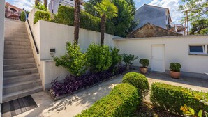 A residential area with a staircase leading to a door, surrounded by lush greenery and palm trees. - Studio with terrace and air conditioning (Crikvenica)