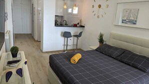 A modern bedroom with a bed, a small desk, and a kitchenette. - Comfortable Studio in Marbella With sea Views (Marbella)