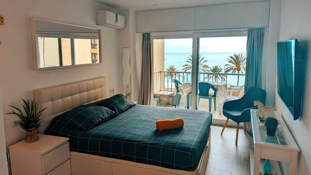 A bedroom with a large bed, a bedside table, a mirror, and a view of the sea through a balcony. - Comfortable Studio in Marbella With sea Views (Marbella)