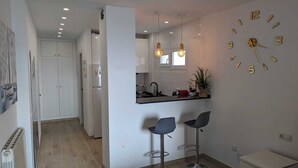 A modern kitchen with a black countertop, two bar stools, and a wall clock. - Comfortable Studio in Marbella With sea Views (Marbella)