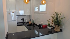 A modern kitchen with white cabinets, a black countertop, and two pendant lights. - Comfortable Studio in Marbella With sea Views (Marbella)