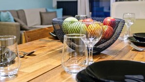 Et spisebord med en frugtkurv, vinglas og bestik.