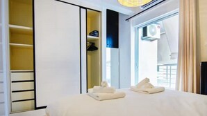 Et hotelværelse med seng, garderobeskab og et vindue med klimaanlæg.