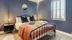 Une chambre à coucher avec un lit, une table de chevet et une fenêtre avec des stores.