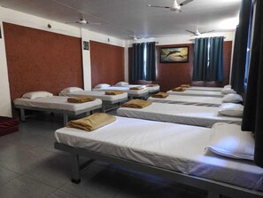 A hotel room with multiple single beds, each with a white mattress and a brown blanket. - The Stream Resort (Shrivardhan)