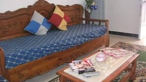 Une chambre à coucher avec un lit en bois, une table de chevet avec des magazines et un arrangement floral.