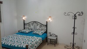 Une chambre à coucher comprenant un lit, des lampes de chevet, une petite table et un présentoir décoratif en métal.