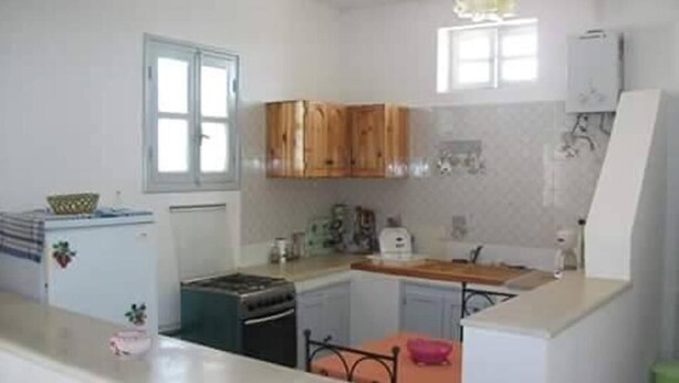 Une cuisine de taille réduite, dotée de meubles de rangement en bois, d’un réfrigérateur et d’une cuisinière.