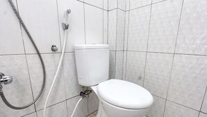 A bathroom with a toilet, a shower, and a toilet paper holder.