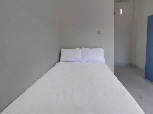 A narrow, single-bed room with white bedding and a plain, light-colored wall. - OYO Life 92769 Janigo Kos (Kuala Lipis)