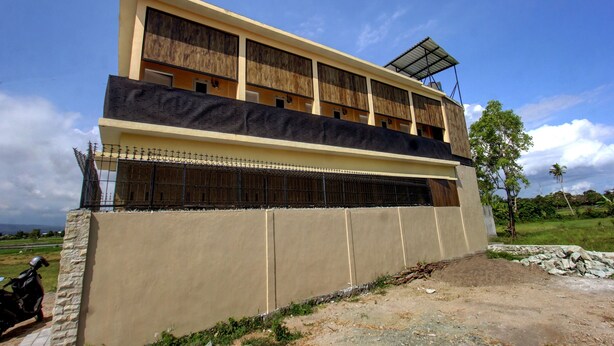 A multi-story building with a flat roof and a balcony on the upper floor.