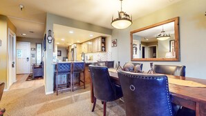 A dining area with a wooden table and chairs, a chandelier, and a large mirror on the wall. - Pet-Friendly, Private Hot Tub, Washer/Dryer & Gas Grill. Beautiful Views (Mammoth Lakes)