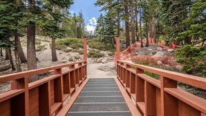 A wooden bridge with metal grating leading to a forested area. - Pet-Friendly, Private Hot Tub, Washer/Dryer & Gas Grill. Beautiful Views (Mammoth Lakes)