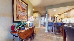 A kitchen with wooden cabinets, a bar area with blue cushioned seating, and a dining table with a plaid tablecloth. - Pet-Friendly, Private Hot Tub, Washer/Dryer & Gas Grill. Beautiful Views (Mammoth Lakes)