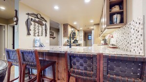 A kitchen with a bar area, wooden cabinets, and a tiled backsplash. - Pet-Friendly, Private Hot Tub, Washer/Dryer & Gas Grill. Beautiful Views (Mammoth Lakes)