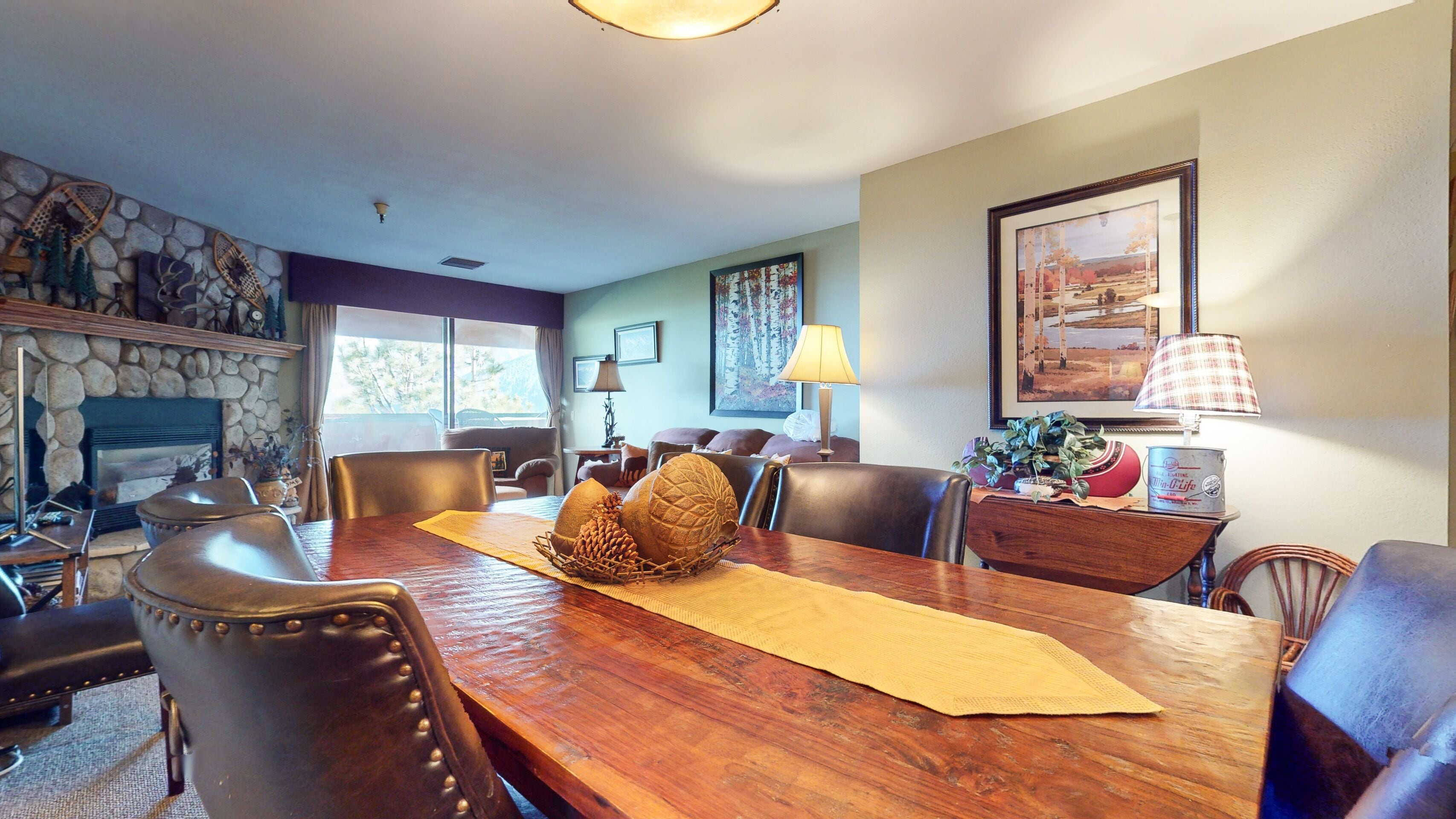 Uma sala de jantar com mesa de madeira, cadeiras de couro, lareira e parede de pedra.