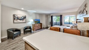 Ein modernes Schlafzimmer mit einem großen Bett, einem Schreibtisch und einem Stuhl. Außerdem ist ein Schminktisch und ein Bild an der Wand zu sehen.