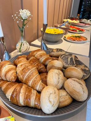 A buffet with a variety of baked goods including croissants and bread rolls. - Trugstad Gård (Nannestad)